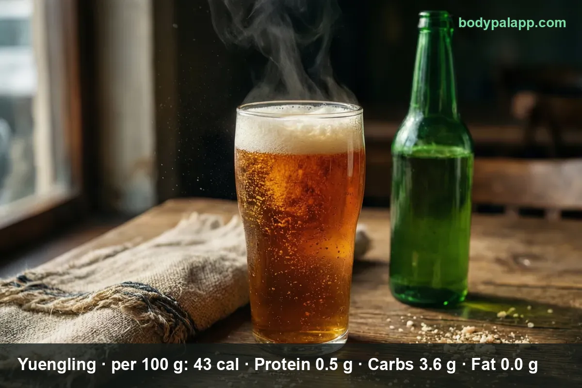 Pint of amber lager with a thick foam head and cold mist beside a plain green unlabeled beer bottle